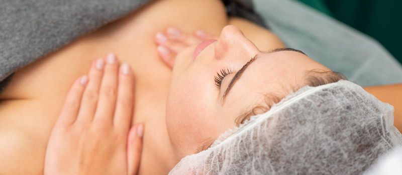 Massaging female chest. Young beautiful caucasian woman with closed eyes getting chest massage at beauty spa salon