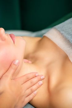 Massaging female neck. Young caucasian woman receiving neck massage relaxing in spa salon