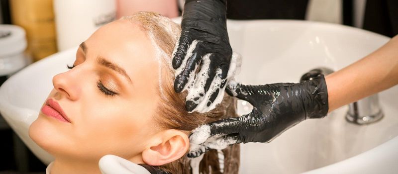 Young caucasian blonde woman having hair washed in the sink at a beauty salon