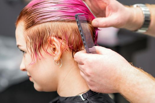 Styling female hair. Male hairdresser makes hairstyle for a young woman in a beauty salon