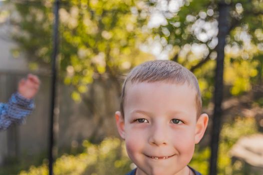 little boy jumps on a trampoline that stands in the yard