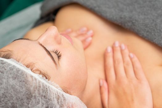 Massaging female chest. Young beautiful caucasian woman with closed eyes getting chest massage at beauty spa salon
