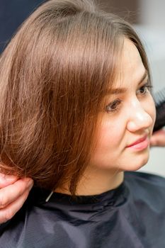 Styling female hair. Male hairdresser makes hairstyle for a young woman in a beauty salon