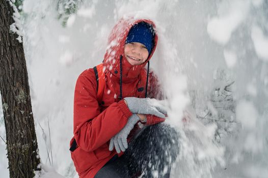 Portrait of teenage boy walking and having fun in winter snowing forest
