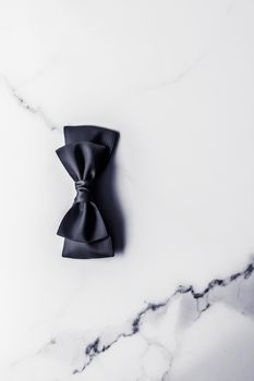 Holiday gift, decoration and sale promotion concept - Black silk ribbon and bow on marble background, flatlay