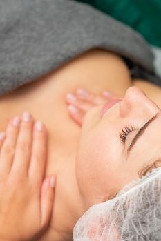 Massaging female chest. Young beautiful caucasian woman with closed eyes getting chest massage at beauty spa salon