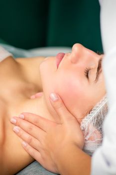 Massaging female neck. Young caucasian woman receiving neck massage relaxing in spa salon