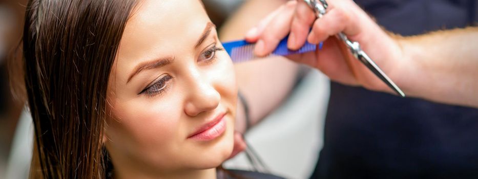 Styling female hair. Male hairdresser makes hairstyle for a young woman in a beauty salon