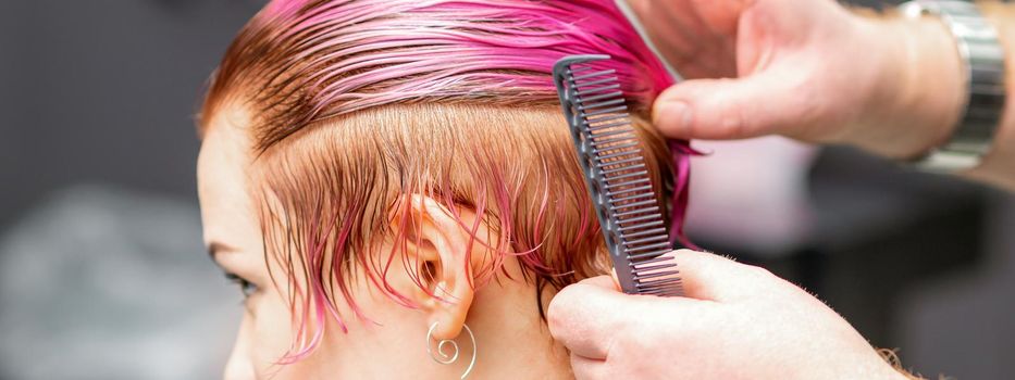 Styling female hair. Male hairdresser makes hairstyle for a young woman in a beauty salon