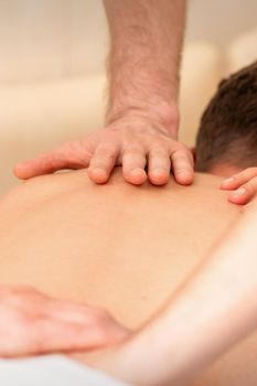 Young man receiving back massage in four hands in spa beauty salon