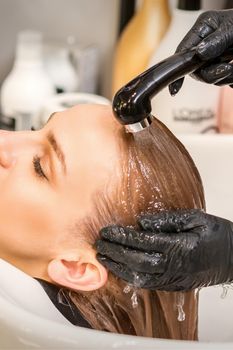 Young caucasian blonde woman having hair washed in the sink at a beauty salon