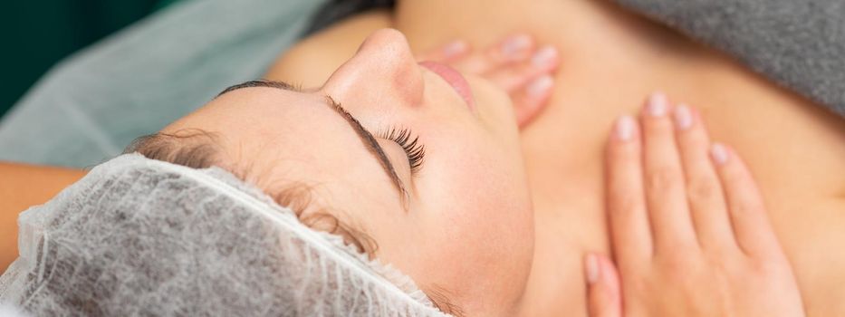 Massaging female chest. Young beautiful caucasian woman with closed eyes getting chest massage at beauty spa salon