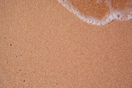 A soft wave runs on a sandy shore on a summer day. Empty space can be used as background for display or montage your top view products.