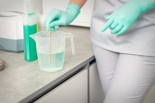 The beautician uses a stick to mix disinfectant into the water. Sterilization of tools