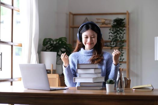 Asian woman celebrate with laptop, success happy pose. E-commerce, University education, internet Technology, or startup small business concept. Modern office or living room with copy space.