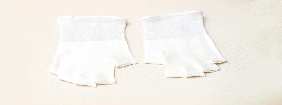 White bamboo fingerless inner gloves for cosmetic procedures lying on white