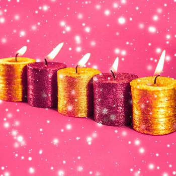 Winter, celebration and new years eve concept - Christmas candles and shiny snow on pink background, holiday season decoration