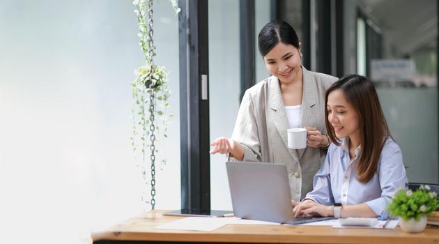 Two Young Asian businesswoman discuss with new startup project Idea presentation, analyze planning and financial statistics and investment market at office..