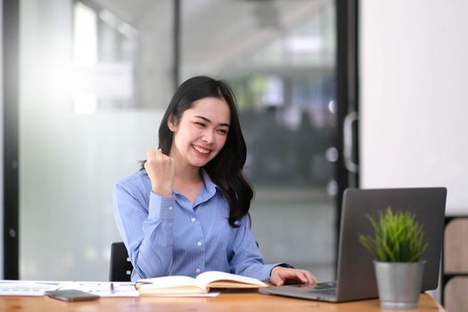 Pretty Asian businesswoman sitting on a laptop And the work came out successfully and the goal was achieved, happy and satisfied with her..