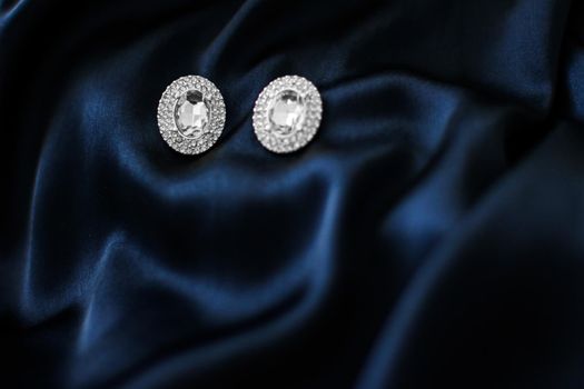 Jewellery brand, elegant fashion and bridal luxe gift concept - Luxury diamond earrings on dark blue silk background, holiday glamour jewelery present