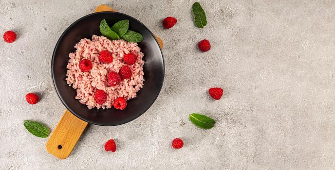 Healthy food on gray concrete background. Fresh raspberries risotto on a delicate and elegant dish