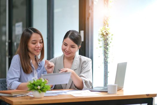 Two Young Asian businesswoman discuss with new startup project Idea presentation, analyze planning and financial statistics and investment market at office..