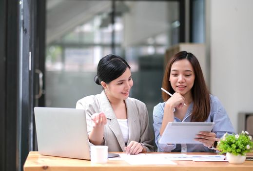 Two Young Asian businesswoman discuss with new startup project Idea presentation, analyze planning and financial statistics and investment market at office..