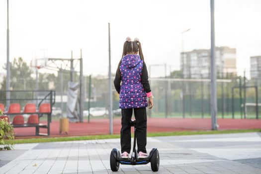 A little girl riding a electric scooter. Personal eco transport, gyro scooter, smart balance wheel. Popular electric transport.