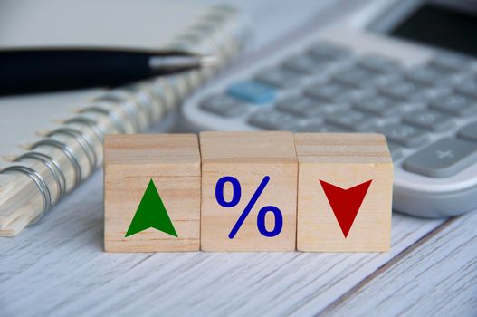 Wooden blocks with icon percentage and symbol arrow up and down. Business and Interest fluctuation concept.