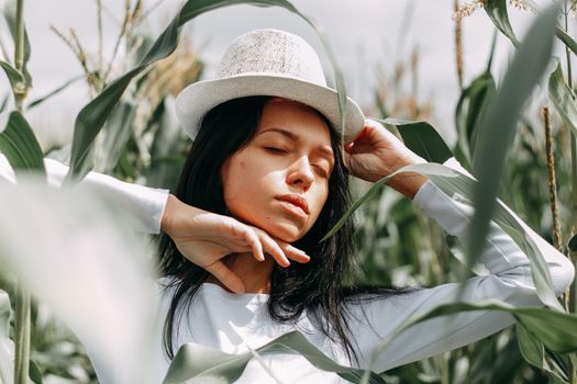 A brunette girl in a white dress in a cornfield. The concept of harvesting.
