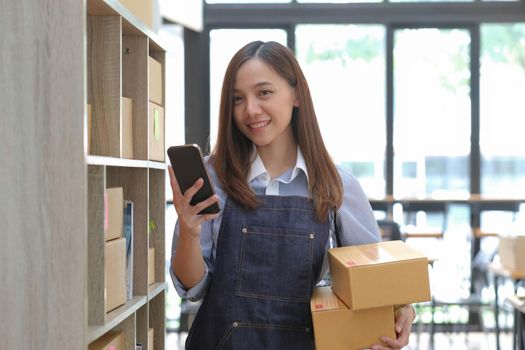 Startup small business entrepreneur SME, asian woman receive order on phone. Portrait young Asian small business owner home office, online sell marketing delivery, SME e-commerce telemarketing concept.