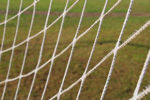 The grid from the old football goal close-up on the background of the football field.