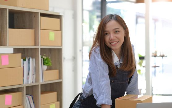 Portrait of Asian young woman SME working with a box at home the workplace.start-up small business owner, small business entrepreneur SME or freelance business online and delivery concept..