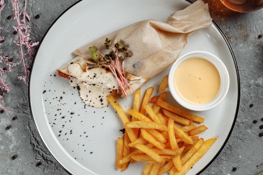 Shawarma Sandwich with French Fires and Salt Grinder on Dark Background.