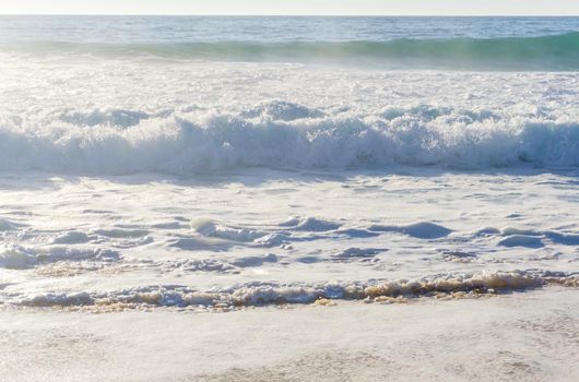 Ocean waves with white foam on a sunny day background