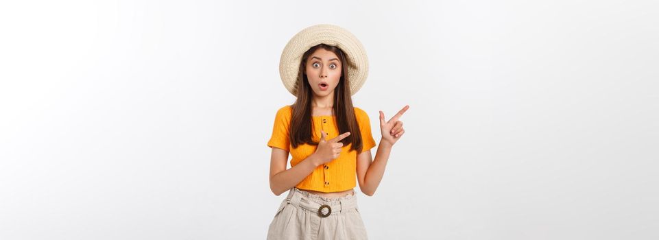 Teenager girl on summer vacation surprised and pointing finger on copy space over isolated white background