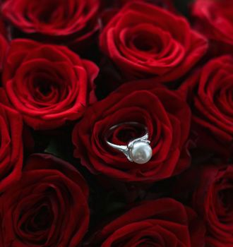 Gemstone jewellery, wedding present and engagement proposal concept - Beautiful white gold pearl ring and bouquet of red roses, luxury jewelry love gift on Valentines Day and romantic holidays