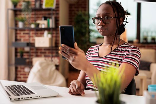 Employee talking on video call, woman working in home office. Remote project manager chatting with team on online meeting, freelancer attending teleconference on smartphone