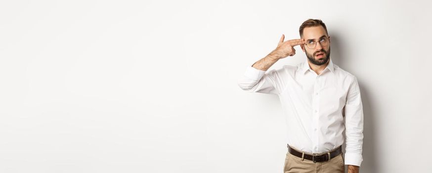 Annoyed man making shooting in head and roll eyes, standing distressed over white background.