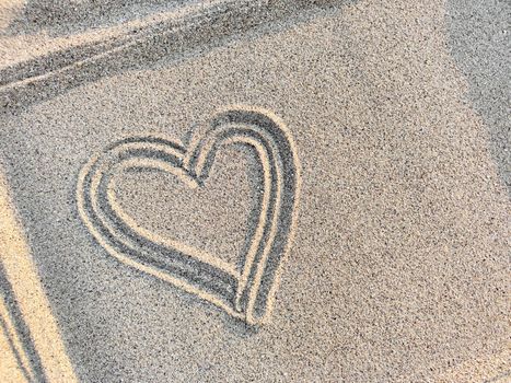 Concept of love and health. Heart drawn on the sand in a frame, top view, close-up. Copy space.