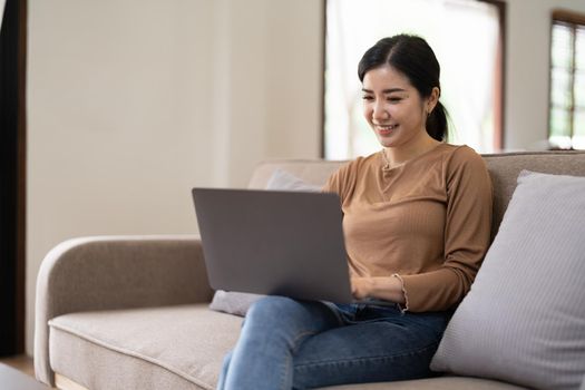 Young asian woman having conversation chatting while using laptop at house. Work at home, Video conference, Online meeting video call, Virtual meetings, Remote learning and E-learning.