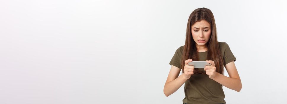 Happy attractive brunette girl joying win in video game on smartphone, isolated over grey background.