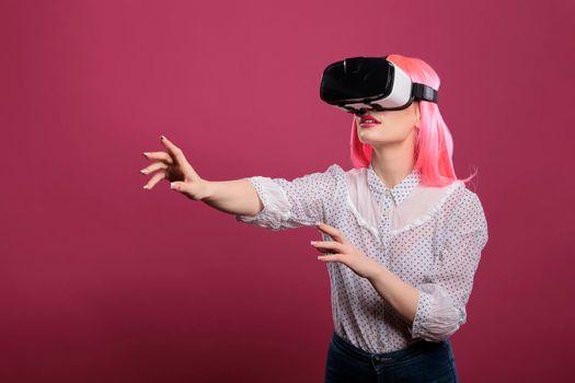 Beauty model using virtual reality glasses with 3d vision, interactive visual simulation on vr goggles. Electronic futuristic experience with augmented tech innovation over pink background.