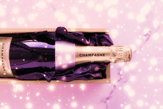 Celebration, drinks and branding concept - Champagne bottle and gift box on pink holiday glitter, New Years, Christmas, Valentines Day, winter present and luxury product packaging for beverage brand