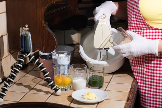 woman cooking spinach muffin step by step, pouring sugar into a bowl, ingredients with mixer, recording video on mobile phone for social media, High quality photo