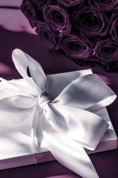 Happy holidays, luxe shopping and love gifts concept - Luxury holiday silk gift box and bouquet of roses on purple background, romantic surprise and flowers as birthday or Valentines Day present