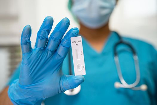 Asian doctor in PPE suit show positive test result with Saliva Antigen Test Kit for check Covid19 coronavirus in hospital.