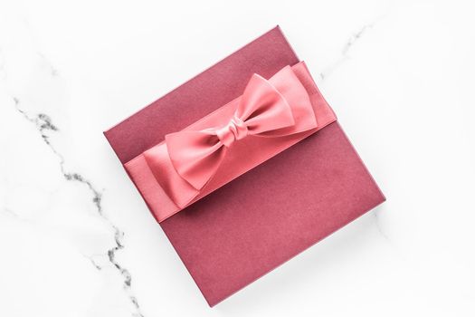 Birthday, wedding and girly branding concept - Coral gift box with silk bow on marble background, girl baby shower present and glamour fashion gift for luxury beauty brand, holiday flatlay art design