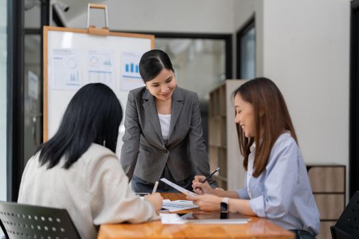 Group of young Asian business people stand talk, consult, discuss working with new startup project idea presentation analyze plan marketing and investment.