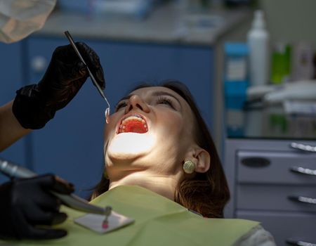 The process of removing braces.Beautiful woman in dental chair during procedure of installing braces to upper and lower teeth. Dentist and assistant working together, dental tools in their hands.